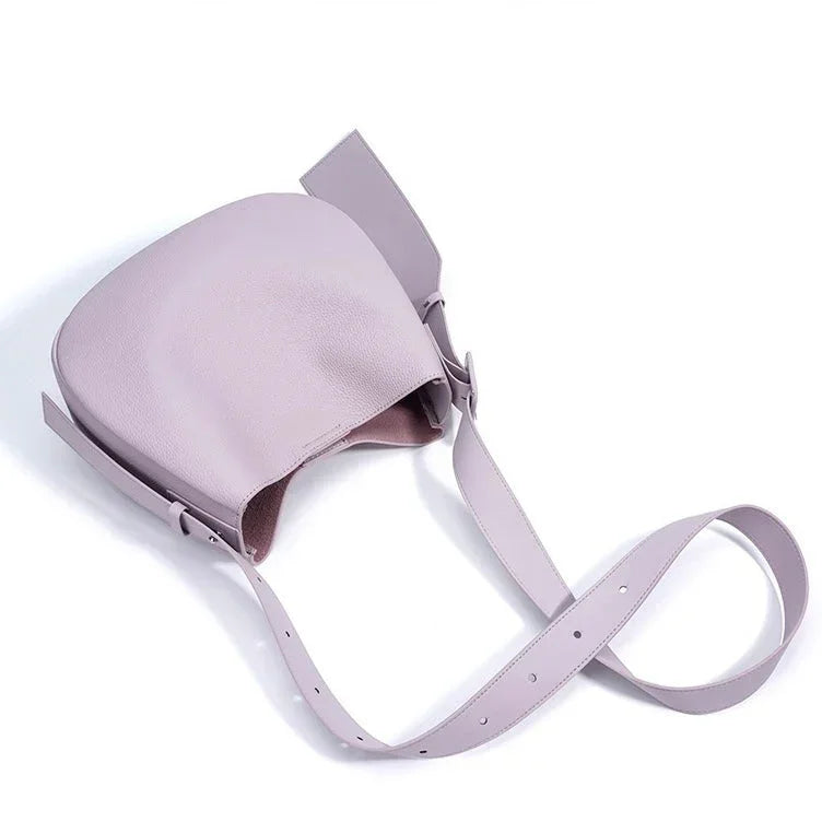 Light purple leather crossbody bag with adjustable strap on white background