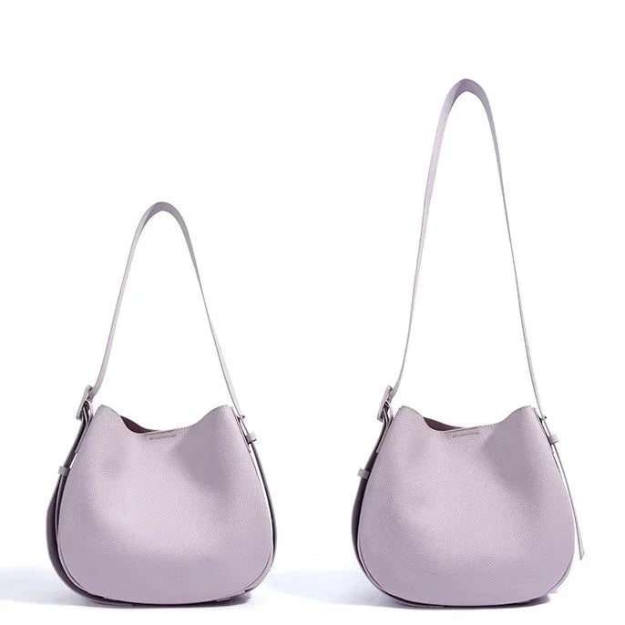 Two light purple leather handbags with shoulder straps on a white background