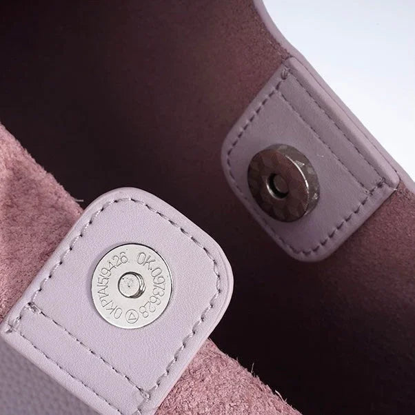 Close-up of pink leather bag magnetic snap closure with stitching detail