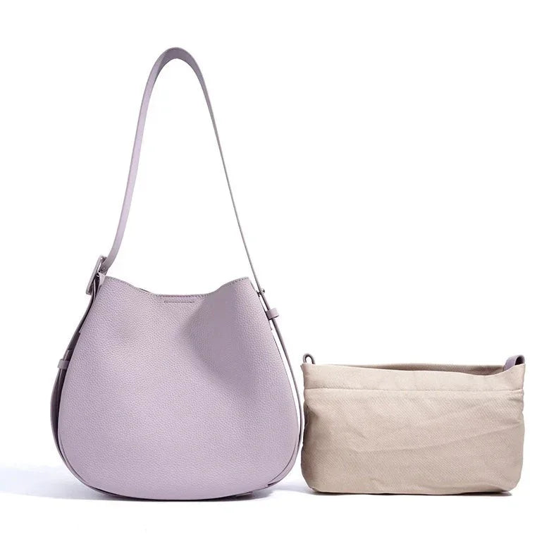 Light purple leather shoulder bag with beige fabric pouch on white background