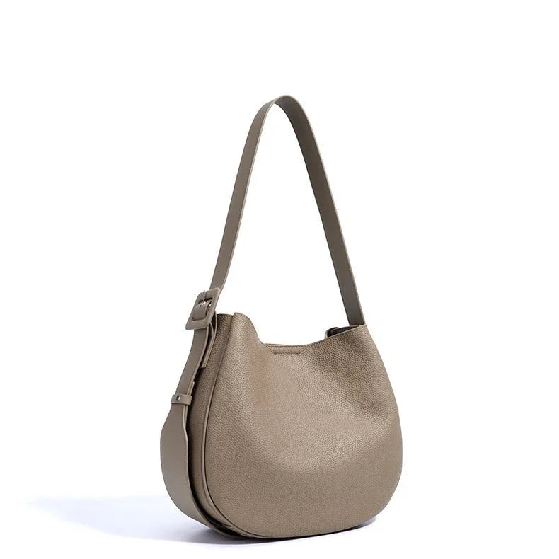 Taupe leather crescent shoulder bag with adjustable strap on white background