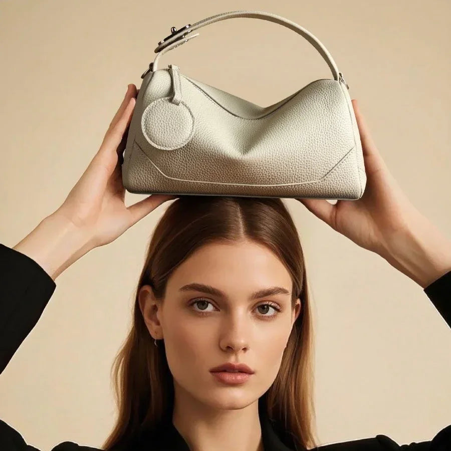 Woman in black suit holding a textured white leather handbag above her head, beige background