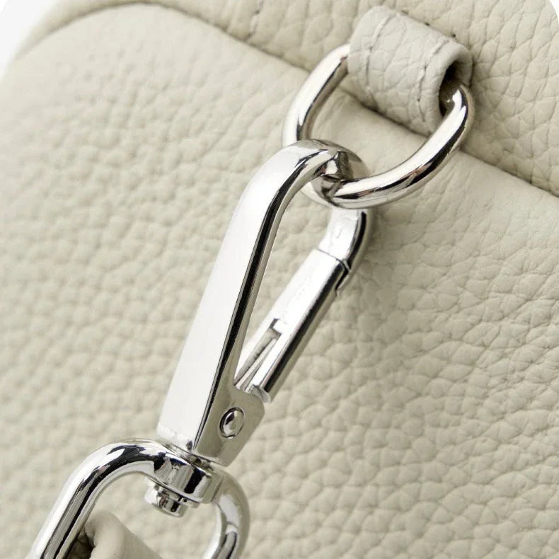 Close-up of silver lobster clasp on textured cream leather handbag