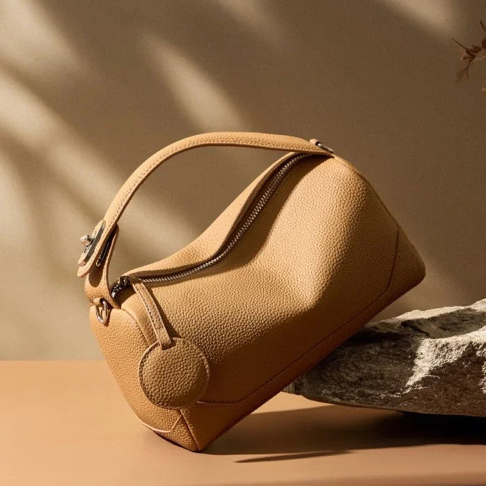 Beige leather handbag with zipper on stone, modern minimalist background