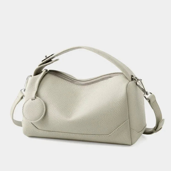 Light gray leather handbag with top handle, zipper closure, and textured finish