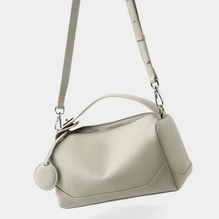 Beige leather crossbody bag with textured finish and adjustable strap on white background