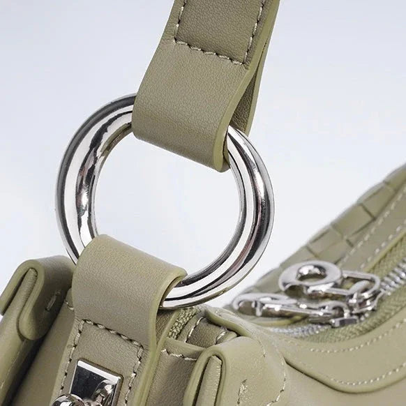 Close-up of sage green handbag with silver ring detail and zipper accents