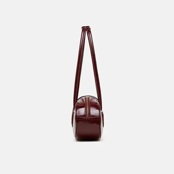 Side view of a maroon leather shoulder bag with double straps on white background