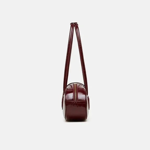 Side view of a maroon leather shoulder bag with double straps on white background