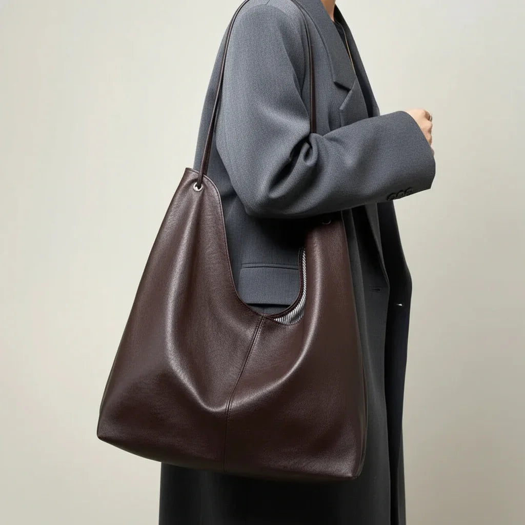 Woman in gray coat carrying large brown leather shoulder bag