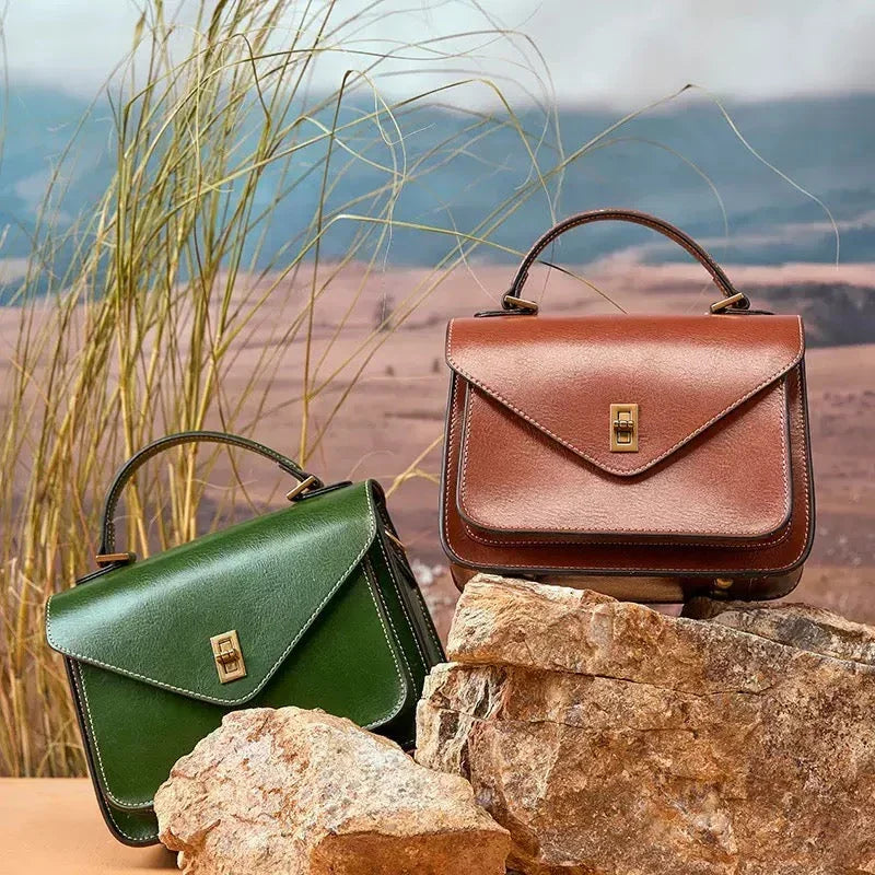 Green and brown leather handbags with top handles on rocks in a nature-inspired outdoor setting