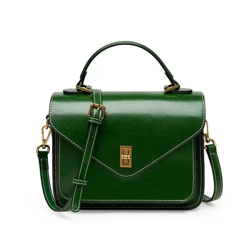 Green leather handbag with gold hardware, top handle, and shoulder strap on white background