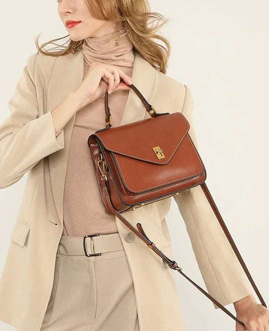 Woman in beige suit holding brown leather crossbody handbag
