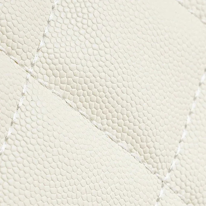 Close-up of cream quilted lizard-embossed leather with visible stitching detail