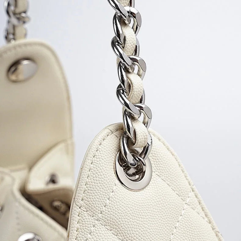 Close-up of white leather quilted handbag with silver chain strap and textured finish