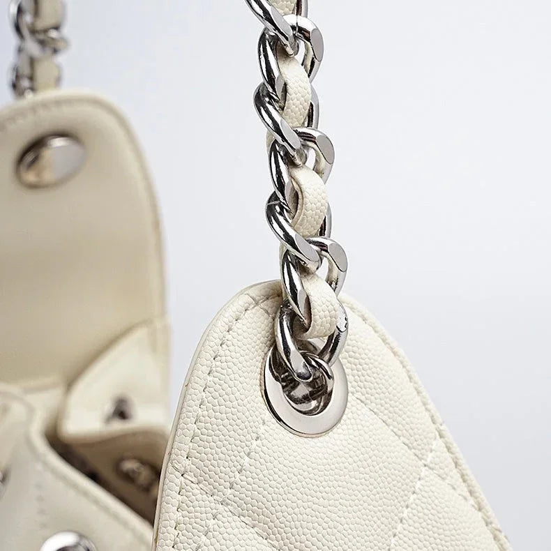Close-up of white leather quilted handbag with silver chain strap and textured finish