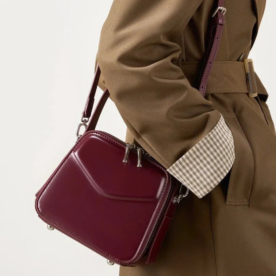 Woman wearing tan coat with maroon square crossbody bag, stylish fashion accessory