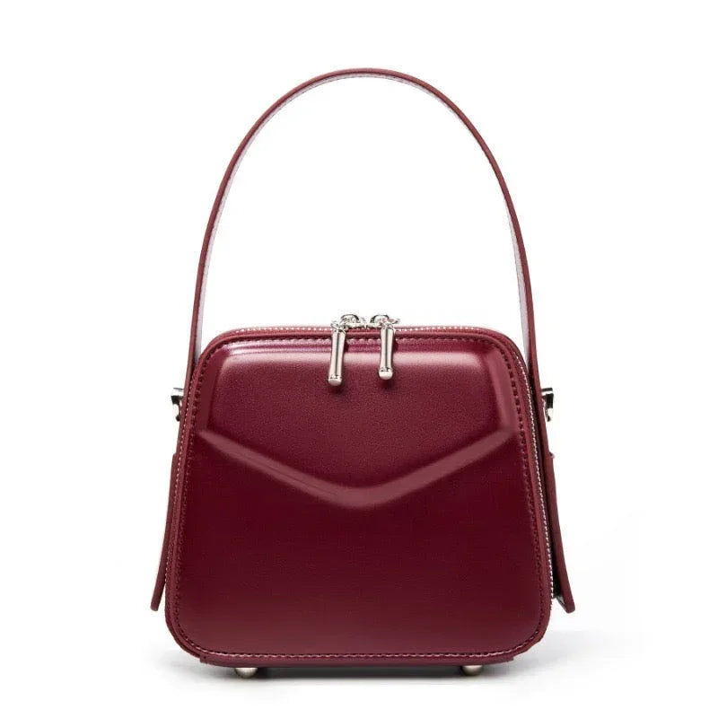 Burgundy leather handbag with structured shape and top handle on white background