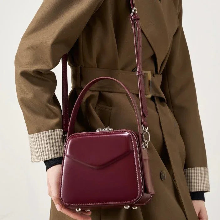 Woman wearing brown trench coat with a burgundy leather crossbody handbag
