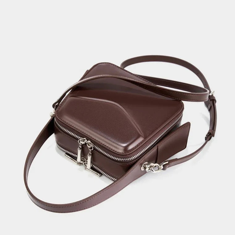 Geometric brown leather crossbody bag with silver zippers and adjustable strap on white background