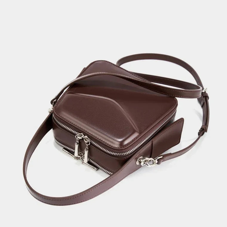 Geometric brown leather crossbody bag with silver zippers and adjustable strap on white background