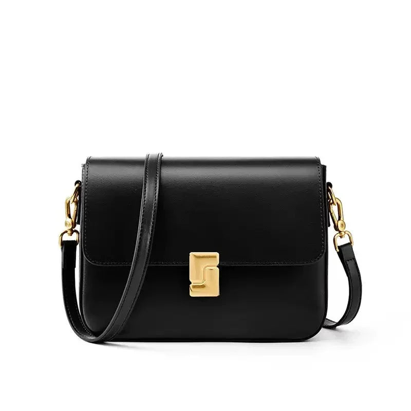 Black leather crossbody bag with gold clasp and hardware on white background