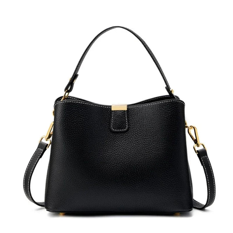 Black leather handbag with gold hardware and removable shoulder strap on white background