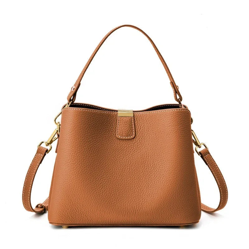 Tan leather handbag with gold hardware and detachable shoulder strap on white background