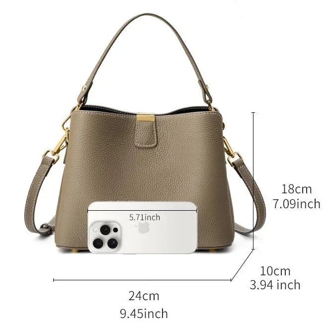 Taupe leather handbag with top handle, gold hardware, and size comparison to smartphone.