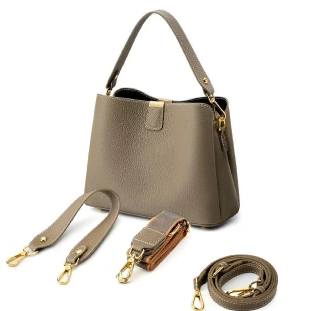Taupe leather handbag with gold hardware and detachable straps on white background