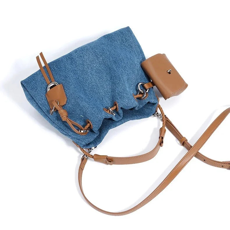 Blue denim bucket bag with brown leather straps and key pouch on white background