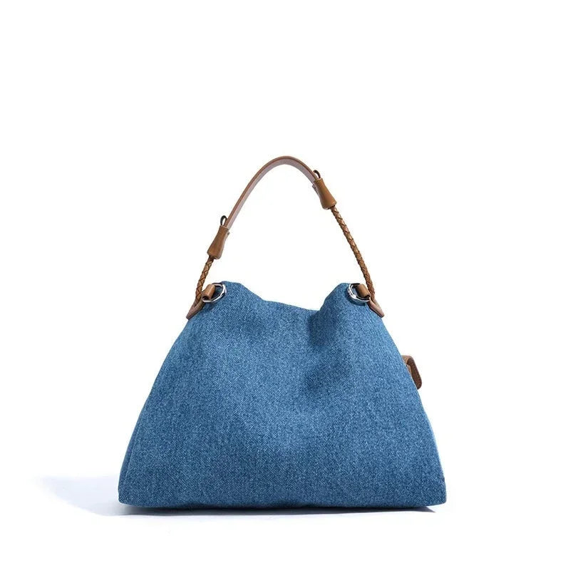 Blue denim tote bag with brown leather handle on white background
