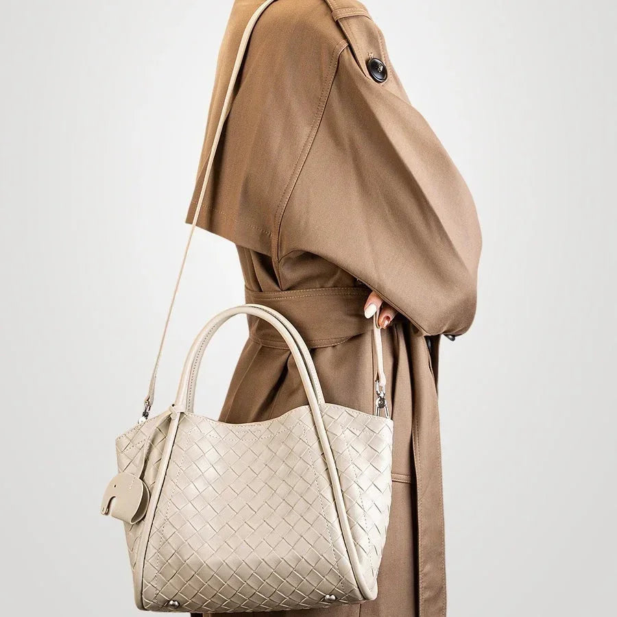 Woman in brown trench coat with beige woven leather handbag and shoulder strap