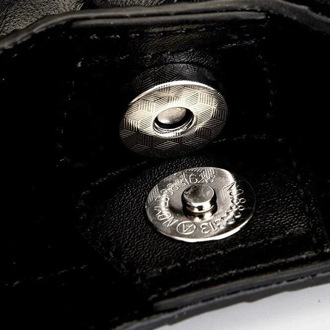 Close-up of a metallic snap button on black leather wallet