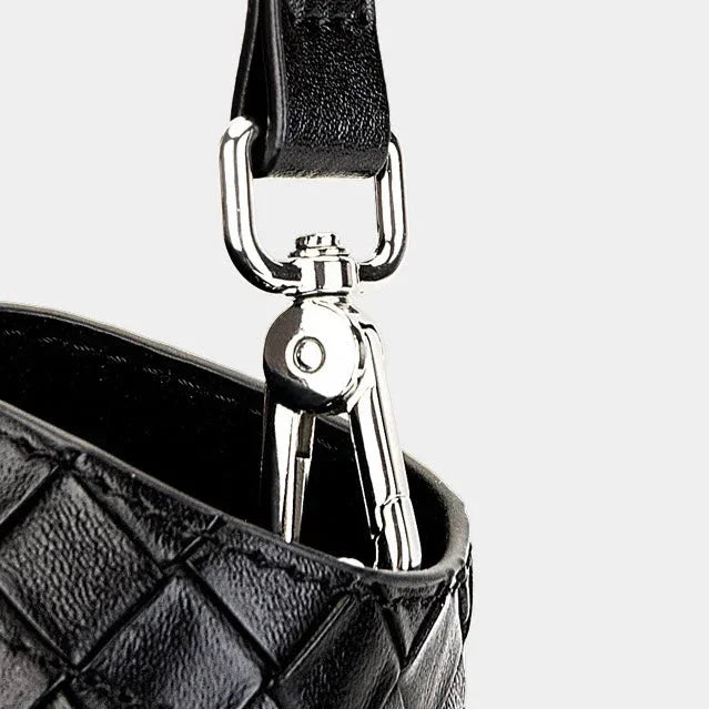 Black leather quilted bag with silver hardware and clasp detail on a light background