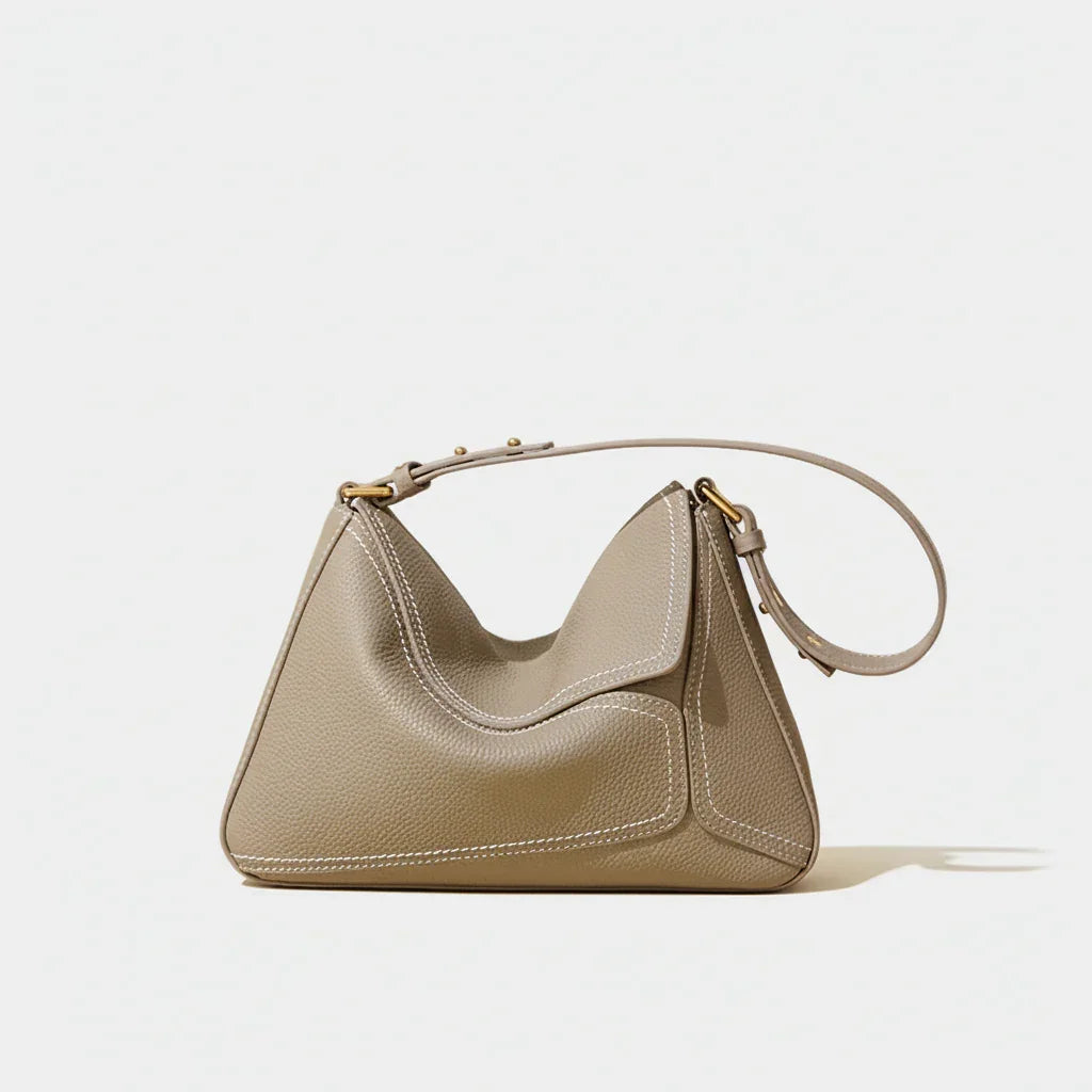 Taupe leather shoulder bag with gold hardware on neutral background