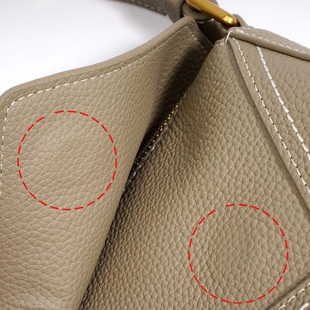 Close-up of textured taupe leather handbag with red circles and white stitching details