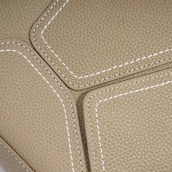 Close-up of beige pebbled leather with white contrast stitching on a luxury bag