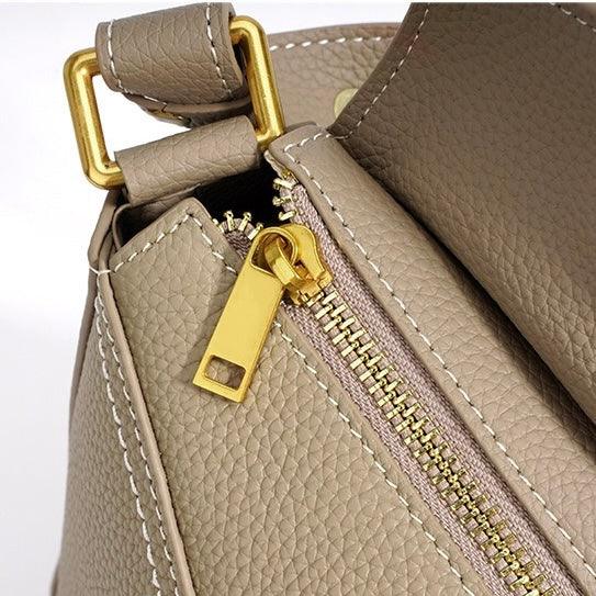 Beige leather handbag with gold zipper and hardware, visible textured stitching