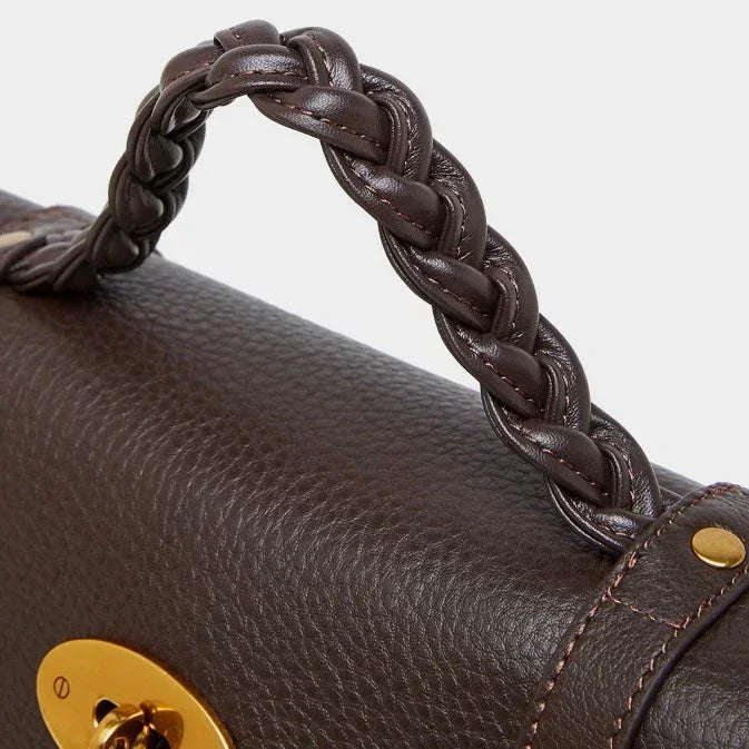 Close-up of brown leather handbag with braided handle and gold hardware