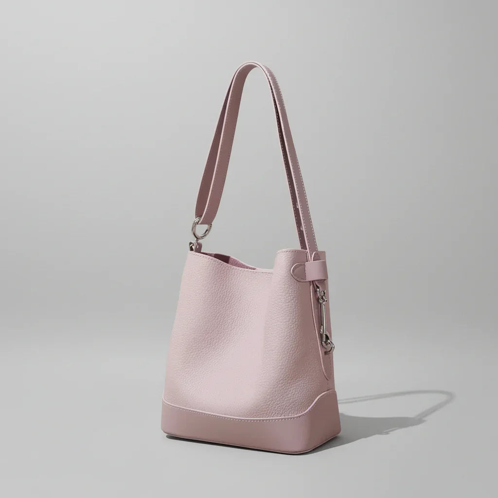 Light pink leather bucket bag with shoulder strap on minimalist background
