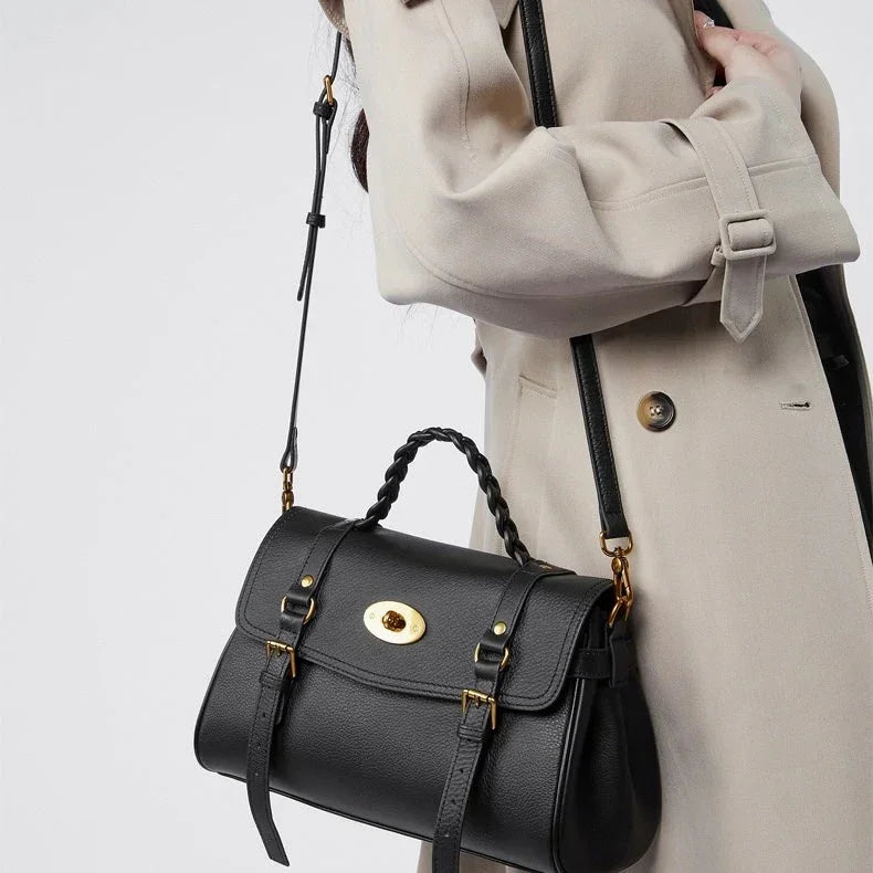 Woman in beige trench coat carrying black leather handbag with gold buckle