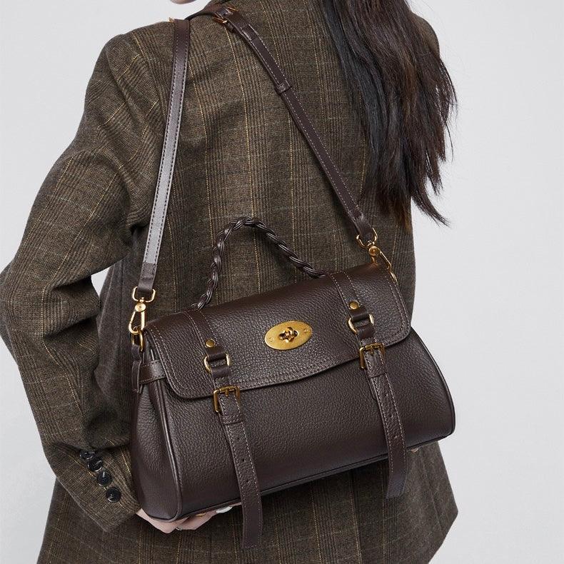 Woman in brown plaid blazer carrying a dark brown leather satchel bag with gold hardware