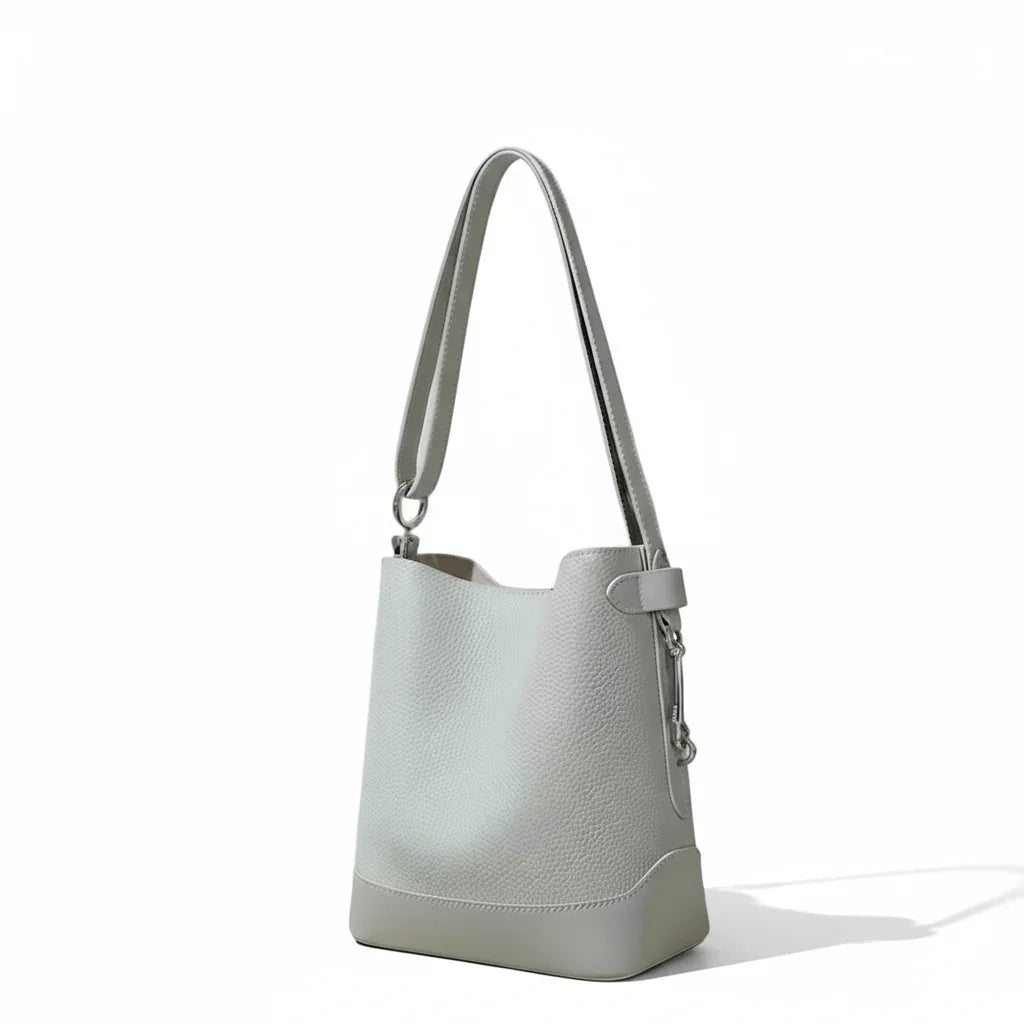 Light gray leather bucket bag with shoulder strap on a neutral background