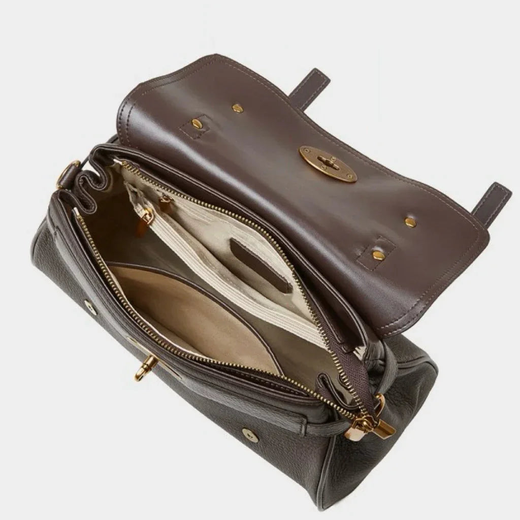 Open brown leather handbag with multiple compartments and gold hardware on white background