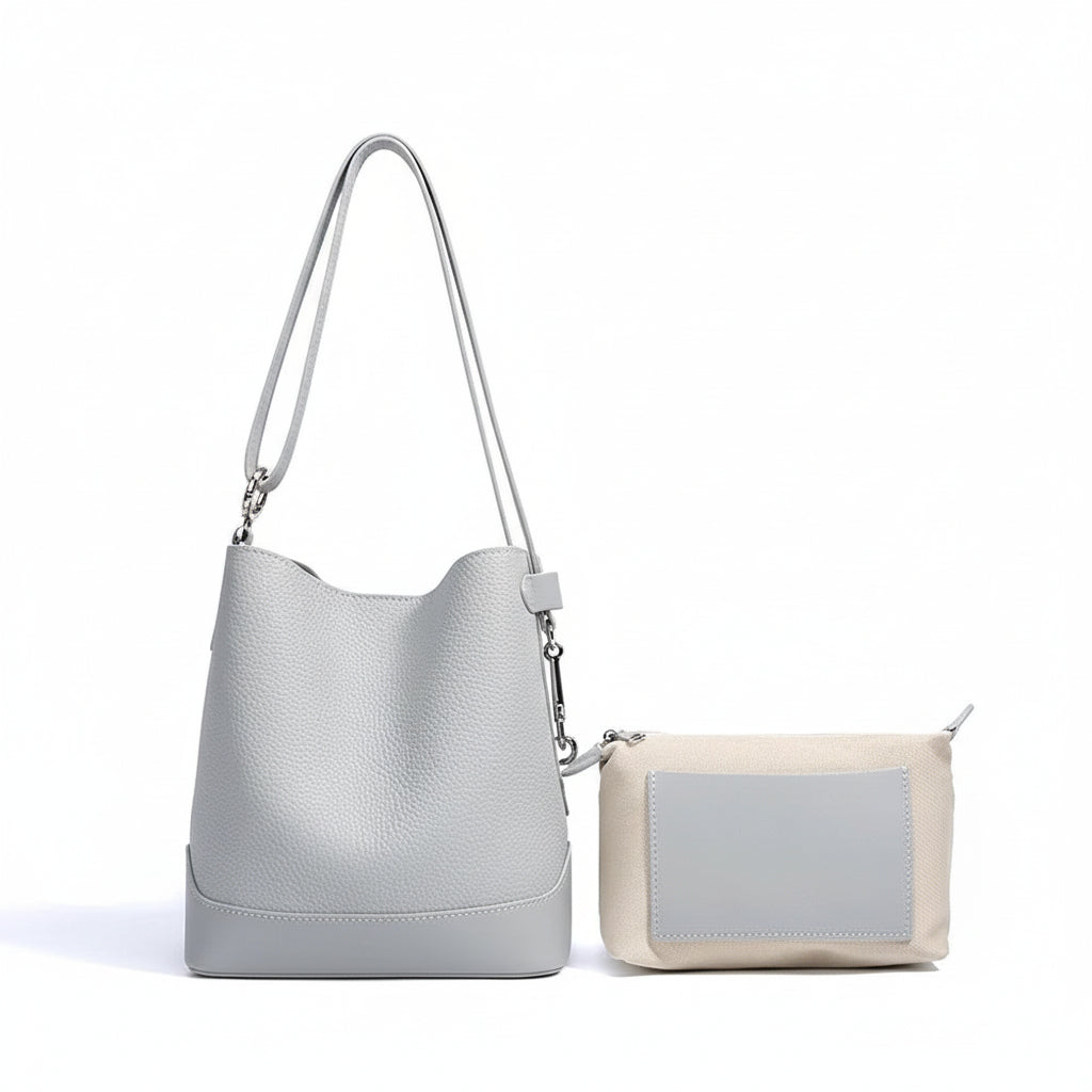 Light grey leather bucket bag with matching beige and grey pouch on white background