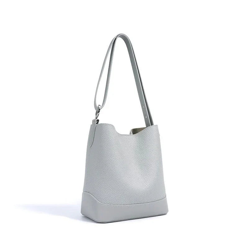 Light gray leather bucket bag with shoulder strap on white background