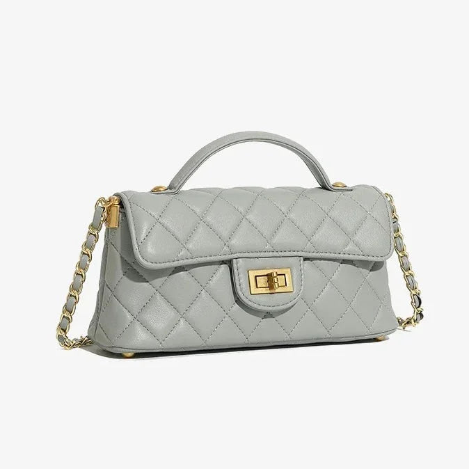 Quilted light gray leather handbag with gold chain strap and turn-lock clasp on white background