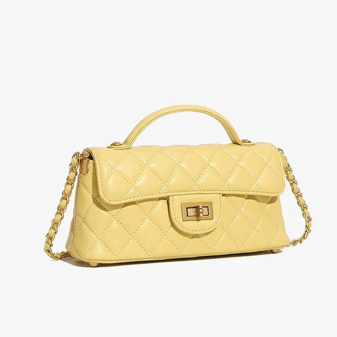 Yellow quilted leather handbag with gold chain strap and top handle on white background