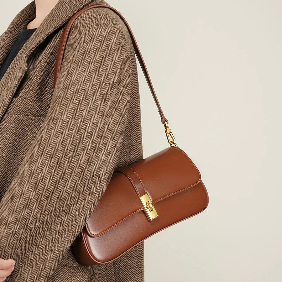 Brown leather shoulder bag with gold clasp on herringbone coat